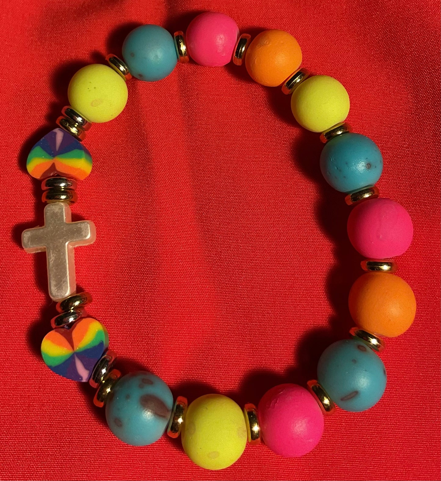 White cross with rainbow accents bracelet on 7 inch elastic thread. Adjustable.