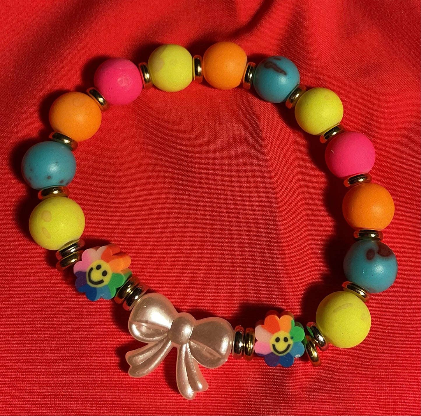 White bow with rainbow accents bracelet on 7 inch elastic thread. Adjustable.