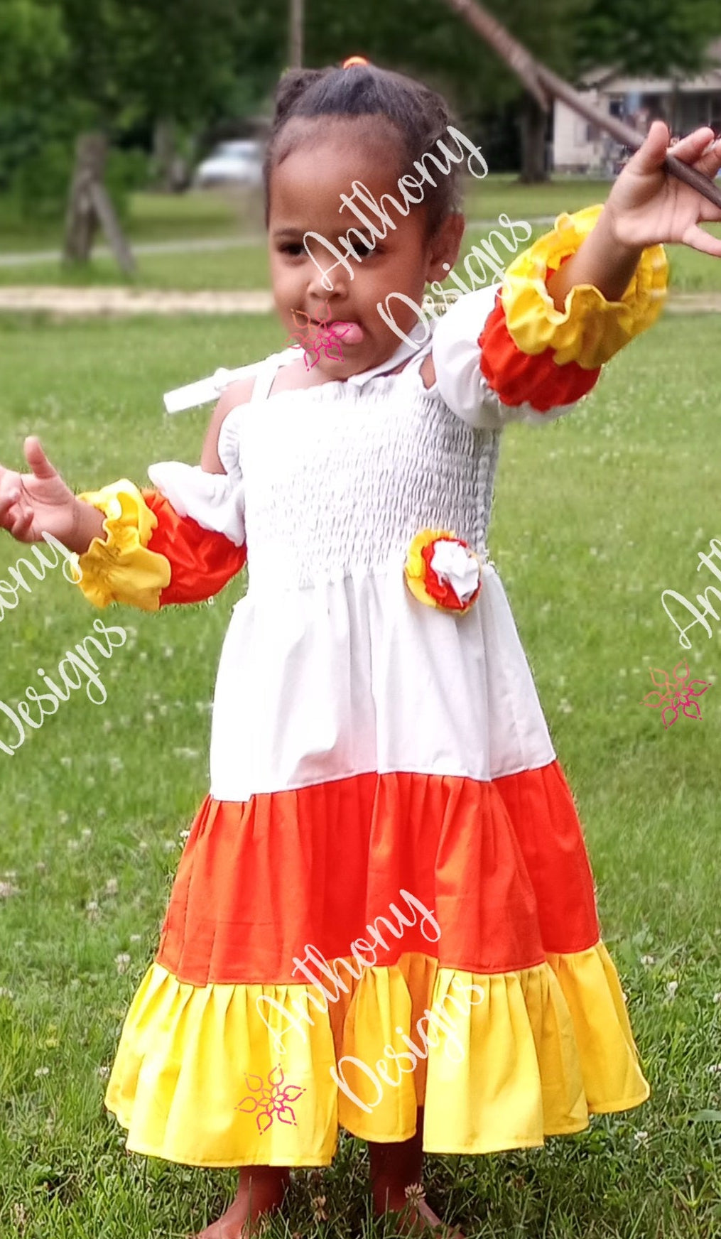 Child wearing a colorful dress with ruffles in a grassy outdoor setting